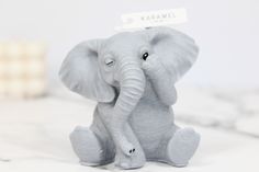 an elephant figurine with a name tag on it's head sitting on a marble surface