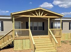 a mobile home with stairs leading up to the front door and second story porch area