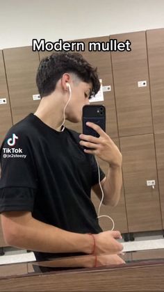 a young man is listening to music on his cell phone while standing in front of lockers