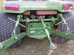 the rear end of a green tractor parked on top of grass