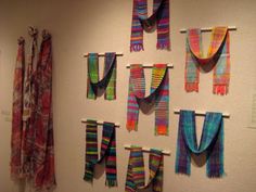 colorful scarves are hung on the wall next to each other in an art gallery