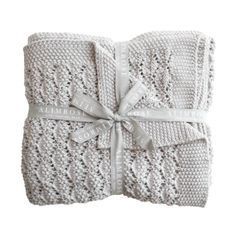 two white knitted blankets tied together with ribbons and bows on them, one is folded in