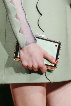 a woman's hand holding a purse with sheer stockings on her arms and legs