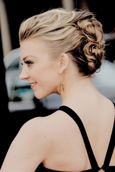 a woman with blonde hair wearing a black dress and gold hoop earrings on her head