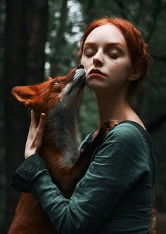 a woman with red hair is kissing a fox