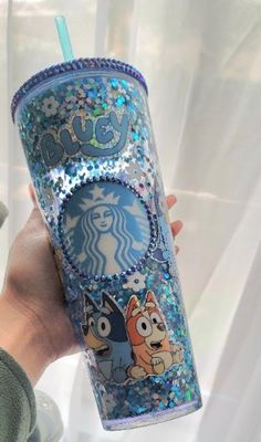 someone holding up a starbucks cup with cartoon characters on it