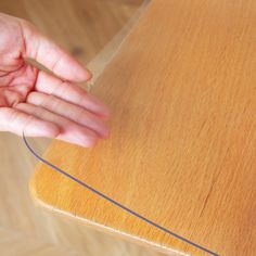 a person's hand reaching for the edge of a wooden table that is made out of plywood