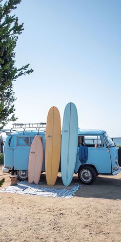 three surfboards stacked on top of each other in front of an old vw bus