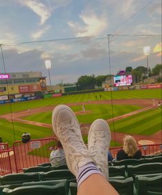 a person with their feet up in the stands at a baseball game on a cloudy day