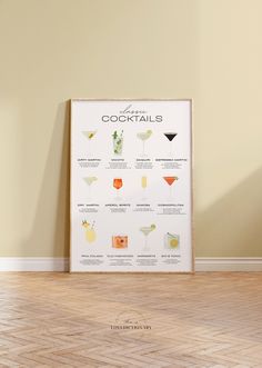 a poster with cocktails on it sitting in front of a wall next to a wooden floor