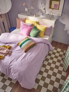 a bed with lots of pillows on top of it and a checkerboard floor