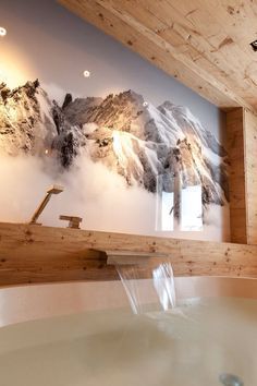 a large tub in the middle of a room with snow covered mountains on the wall