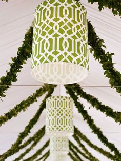 a green and white lamp hanging from a ceiling with greenery on the bottom half