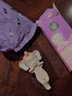 a small plastic toy sitting next to a package of diapers on a wooden table