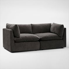 a gray couch with two pillows on it's back and one arm facing the camera