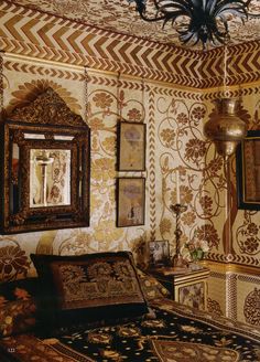 an ornately decorated living room with gold and white wallpaper, chandelier and mirror