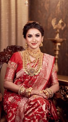 a woman in a red and gold sari sitting on a chair