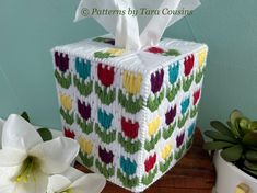 the tissue box is decorated with multicolored hearts and has a white tissue in it