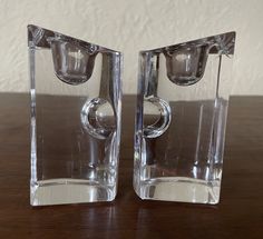 two clear glass vases sitting on top of a wooden table next to each other