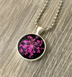 "Pressed Flower Pendant: Bright Pink on Black We \"picked\" the best of our Pressed Flower options and made them available as Pendants! Colorful and cheerful, these lightweight Pendants are made with real pressed flowers and are perfect for everyday wear. Perfect gift for the gardener in your life! ----DETAILS--- * Silver Zinc metal alloy NICKEL + LEAD FREE * 20mm round * slightly domed shape, approx 5mm at it's thickest point * Pressed Flower: Bright Pink on Black * 24\" Nickel Plated Ball Chai Floral Print Flower Necklaces For Gifts, Black Flower Necklace For Gift, Floral Magnets, Green Cherries, Pressed Flower Necklace, Glass Paperweights, Flower Pendant, Flower Necklace, Gifts For Coworkers