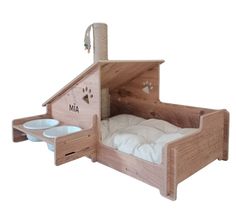 a dog bed made out of wood with its door open and two bowls on the bottom