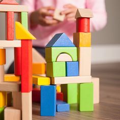 a child playing with wooden blocks on the floor