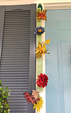 the front door is decorated with colorful fall leaves and fake flowers on it's side