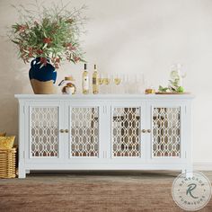 a white cabinet with wine glasses and bottles on it next to a vase filled with flowers