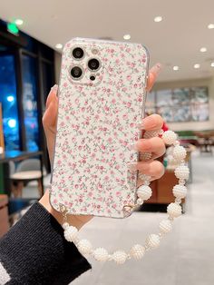 a woman holding up her phone case with flowers on it