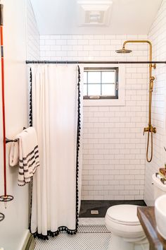 a white bathroom with black and white tile flooring, shower curtain, and toilet