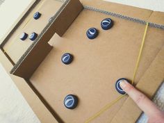 a cardboard box with buttons on it and a hand pointing at the button that is in front of it