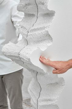 two people standing next to each other with their hands on the wall that has been torn apart