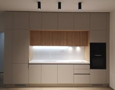 an empty kitchen with white counter tops and wooden cabinets on the wall, under recessed lighting