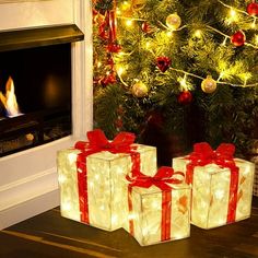 three wrapped presents sitting in front of a fireplace under a christmas tree with lights on it