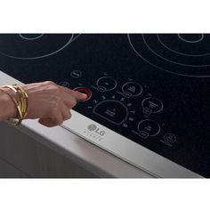 a woman's hand is touching the knob on an electric stove top oven door