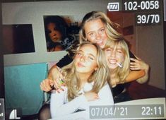 three young women are posing for a photo in front of a television screen with the time on it