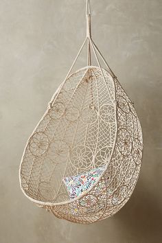 a white hanging basket filled with lots of leafy material on top of a wall