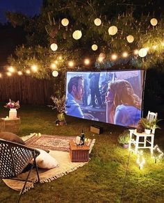 an outdoor movie is set up in the backyard with string lights strung from the trees