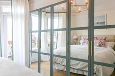 the bedroom is decorated in white and has glass doors that open to let in light