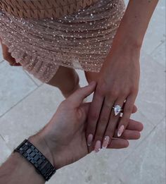 two people holding hands and wearing rings on their fingers, with one person's hand over the other