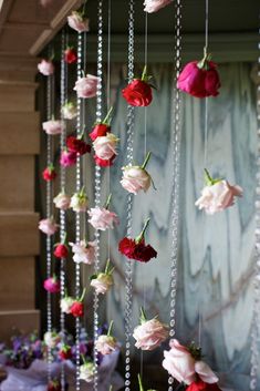 flowers are hanging from the ceiling in front of a wall with beads and chains attached to it