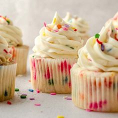 several cupcakes with white frosting and sprinkles