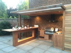 an outdoor kitchen is built into the side of a brick wall and has a grill on it