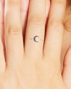 a woman's hand with a small crescent tattoo on it