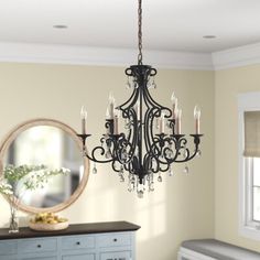 a chandelier hanging from the ceiling in a room with a dresser and mirror