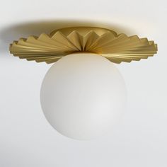 a ceiling light with a white ball hanging from it's center and gold trim