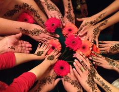 a group of people with their hands on top of each other holding flowers in the middle