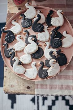 a plate full of decorated cookies with black and white ducks on them sitting on a table