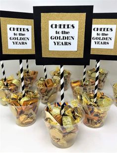 gold and black candy cups with straws in them on a white tablecloth covered table