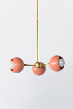 three pink and white balls hanging from a brass chandelier